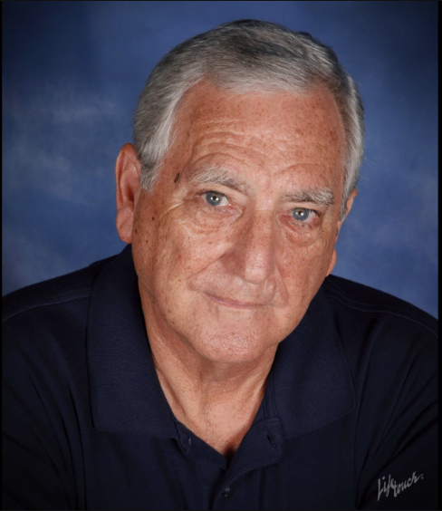 A man with gray hair and wearing a blue shirt.